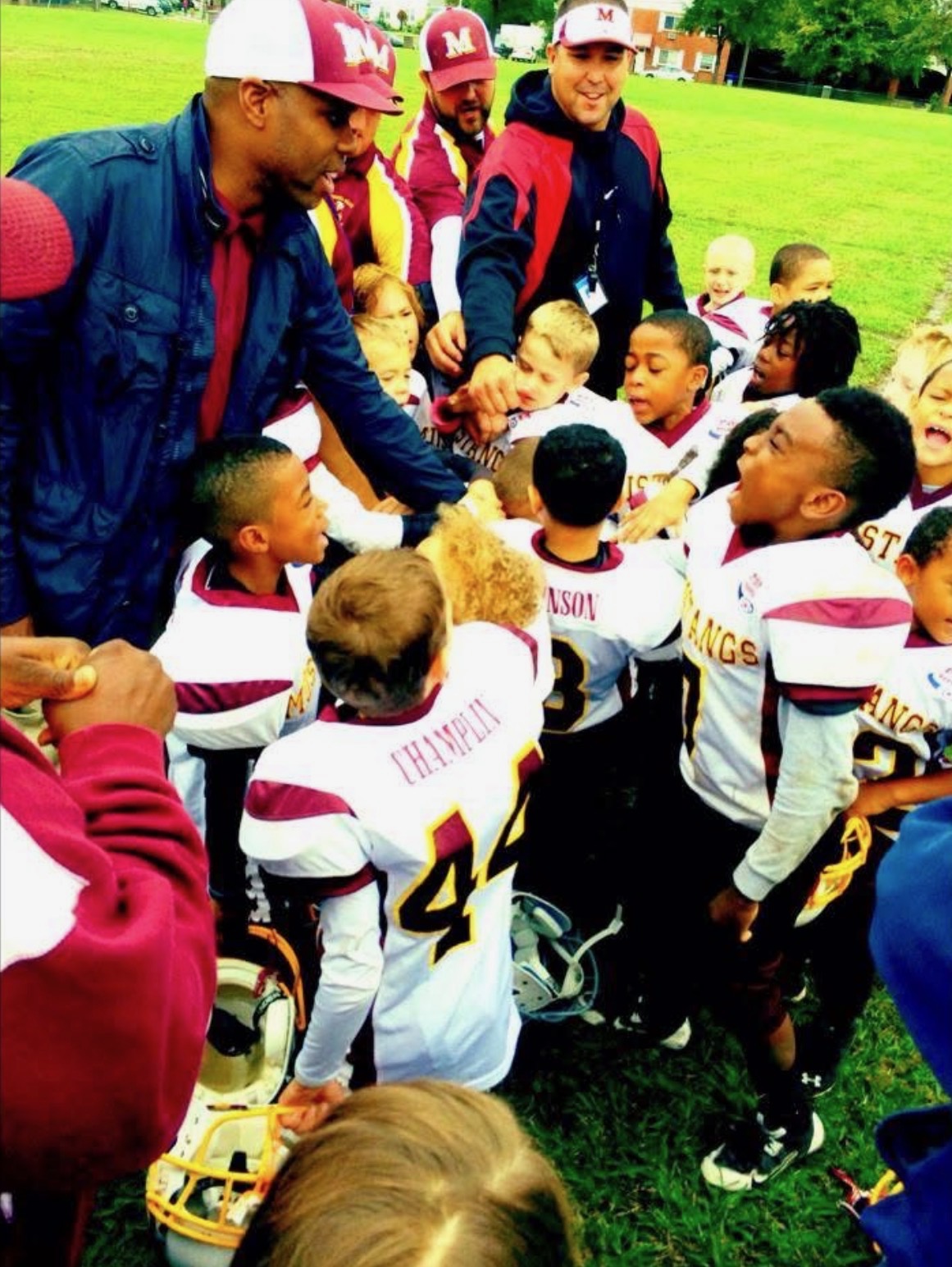 Youth football team huddling with their coaches